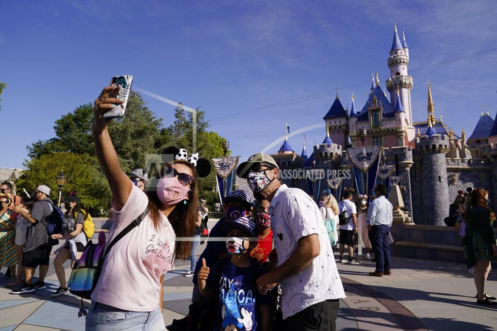 Jae Hong A family takes a photo in front of Sleeping Beauty's Castle at Disneyland in Anaheim, Calif., Friday, April 30, 2021. The iconic theme park in Southern California that was closed under the state's strict virus rules swung open its gates Friday and some visitors came in cheering and screaming with happiness. (AP Photo/Jae Hong)