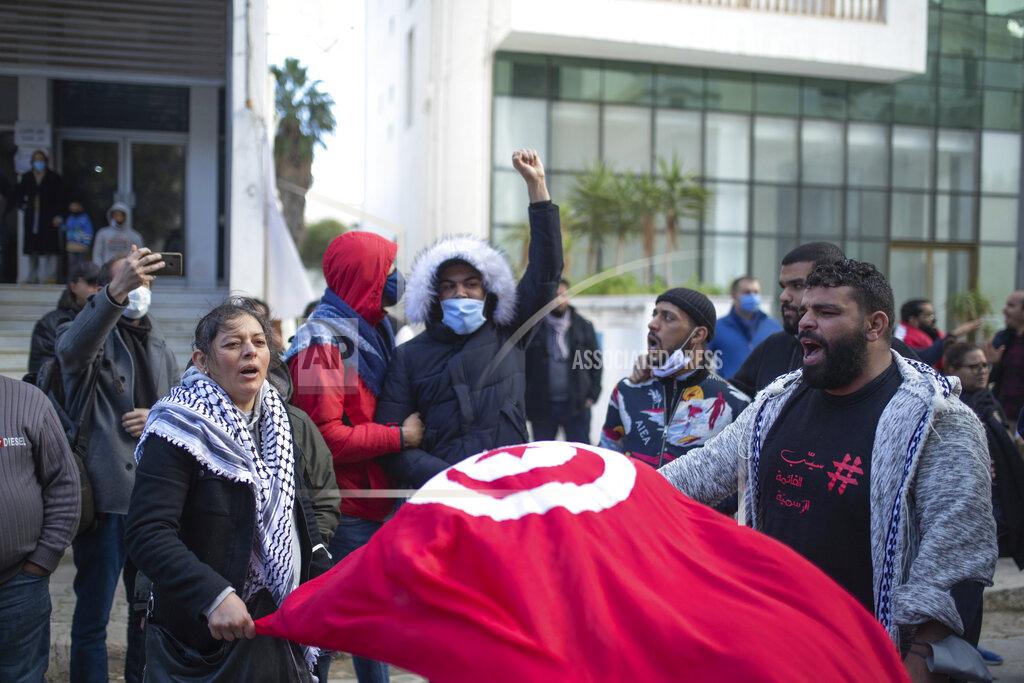 Mosa'ab Elshamy A small group of people take part in a protest on the tenth anniversary of the uprising that toppled longtime autocrat Ben Ali , during to a national lockdown after a surge in COVID-19 cases, in Tunis, Thursday, Jan. 14, 2021. Tunisia is commemorating the 10th anniversary since the flight into exile of its iron-fisted leader, Zine El Abidine Ben Ali, pushed from power in a popular revolt that foreshadowed the so-called Arab Spring. But there will be no festive celebrations Thursday marking the revolution in this North African nation, ordered into lockdown to contain the coronavirus. (AP Photo/Mosa'ab Elshamy)