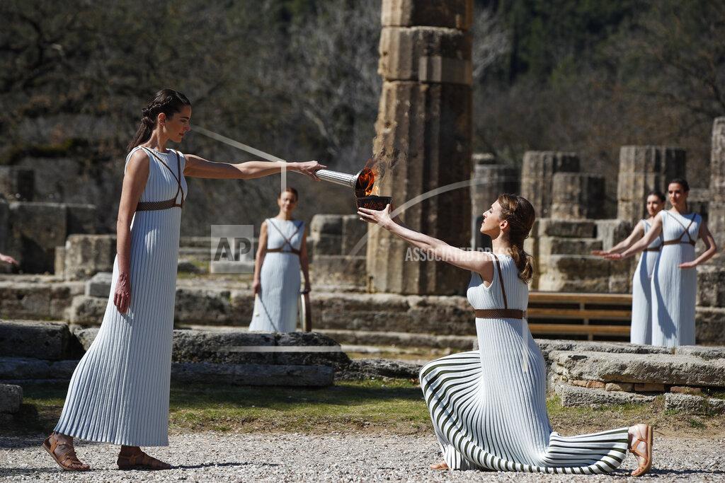 Thanassis Stavrakis Greek actress Xanthi Georgiou, left, playing the role of the High Priestess, holds the torch during the flame lighting ceremony at the closed Ancient Olympia site, birthplace of the ancient Olympics in southern Greece, Thursday, March 12, 2020. Greek Olympic officials are holding a pared-down flame-lighting ceremony for the Tokyo Games due to concerns over the spread of the coronavirus. Both Wednesday's dress rehearsal and Thursday's lighting ceremony are closed to the public, while organizers have slashed the number of officials from the International Olympic Committee and the Tokyo Organizing Committee, as well as journalists at the flame-lighting. (AP Photo/Thanassis Stavrakis)