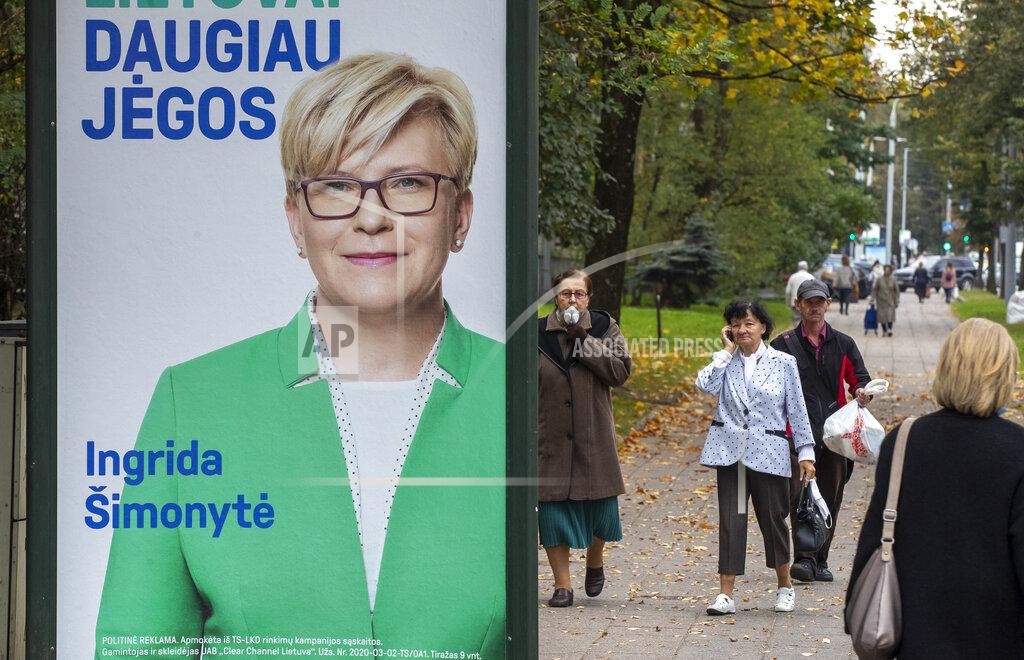 A local resident walk by an election poster showing Lithuania's Homeland Union-Christian Democrats (TS-LKD) party leader Ingrida Simonyte in Vilnius, Lithuania, Friday, Oct. 9, 2020. Lithuanians are voting in the first round of a parliamentary election on Sunday. (AP Photo/Mindaugas Kulbis)