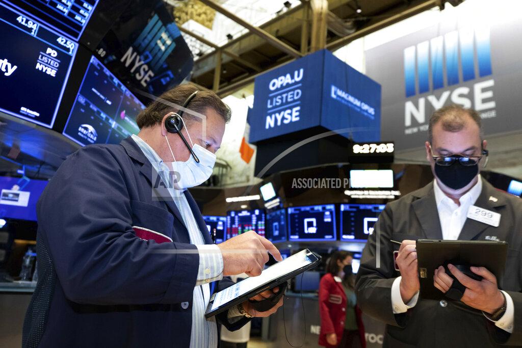 In this photo provided by the New York Stock Exchange, traders John Santiago, left, and William Lawrence, work on the trading floor, Tuesday April 13, 2021. Stocks were choppy and mixed in late morning trading Tuesday as a drop in bond yields hurt bank stocks but helped big technology stocks. (Nicole Pereira/New York Stock Exchange via AP)