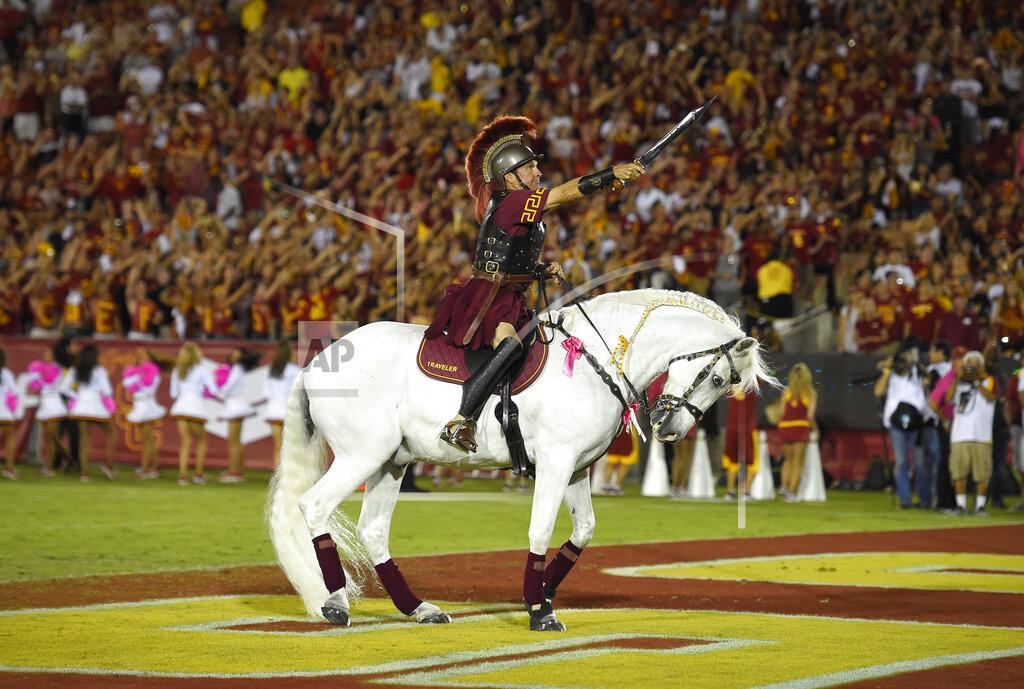 Mark J. Terrill File-Hector Aguilar rides Traveler VII during the second half of an NCAA college football game between Southern California and Utah, Saturday, Oct. 24, 2015, in Los Angeles. Southern Cal's famed white horse, Traveler, won't be galloping triumphantly after a Trojans touchdown. From Ann Arbor to Los Angeles to Oxford, that most American of pursuits, college football, has either given up hope of getting in a traditional season or is flinging what amounts to a Hail Mary pass in a desperate attempt to hang on in the age of Covid-19. (AP Photo/Mark J. Terrill, File)