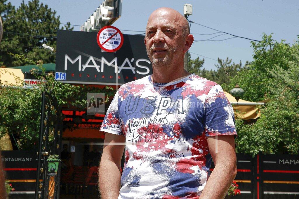Visar Kryeziu Shpetim Pevqeli, 50, who owns Mama’s restaurant poses in front of a sign reading: “Protest, No Entry, for EU citizens without visa,” in Kosovo's capital Pristina, Tuesday, June 28, 2022. The European Union's delay to let Kosovars freely move in its member countries has frustrated them and Pevqeli on Tuesday protested by banning the bloc's citizens at its restaurant. (AP Photo/Visar Kryeziu)