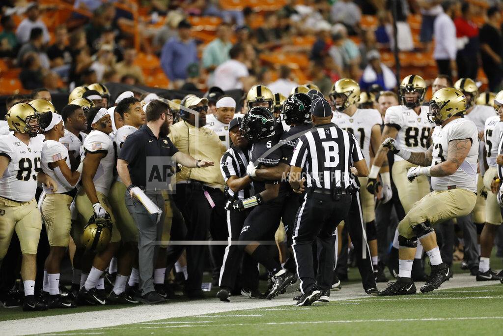 Marco Garcia After shoving Army quarterback Christian Anderson (13) gets out of bounds, Hawaii defensive back Khoury Bethley (5) gets pulled out of the Army bench area after a fracas during the second half of an NCAA college football game Saturday, Nov. 30, 2019 in Honolulu. (AP Photo/Marco Garcia)