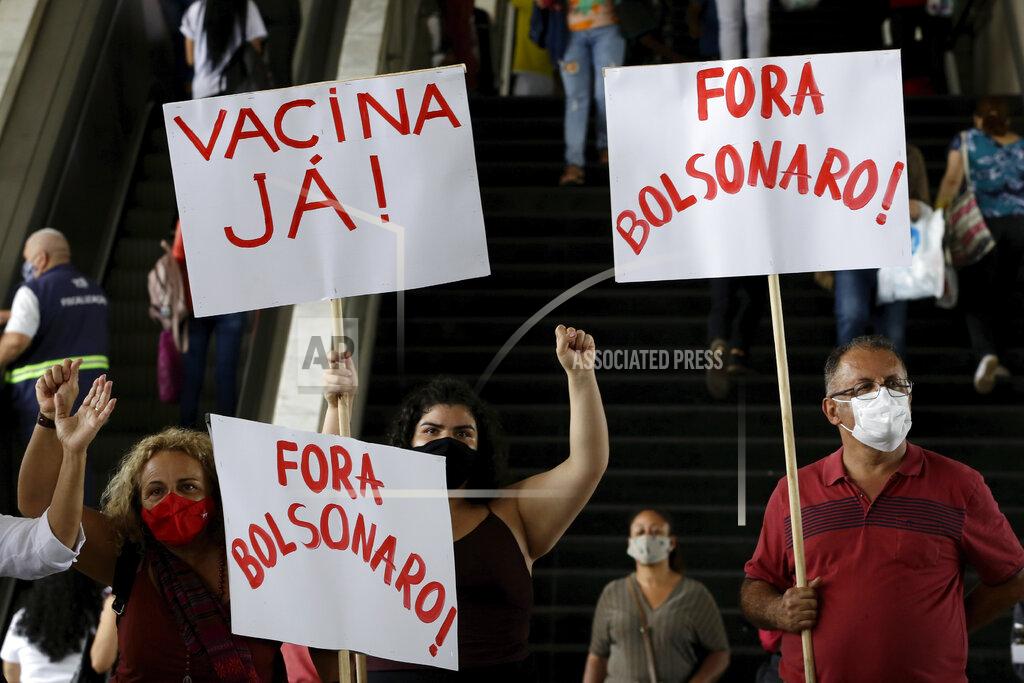 Eraldo Peres Demonstrators hold the Portuguese messages: "Vaccine now!" and "Get out Bolsonaro" to protest Brazilian President Jair Bolsonaro's handling of the coronavirus, at a bus station in Brazilia, Brazil, Wednesday, Dec. 23, 2020. (AP Photo/Eraldo Peres)