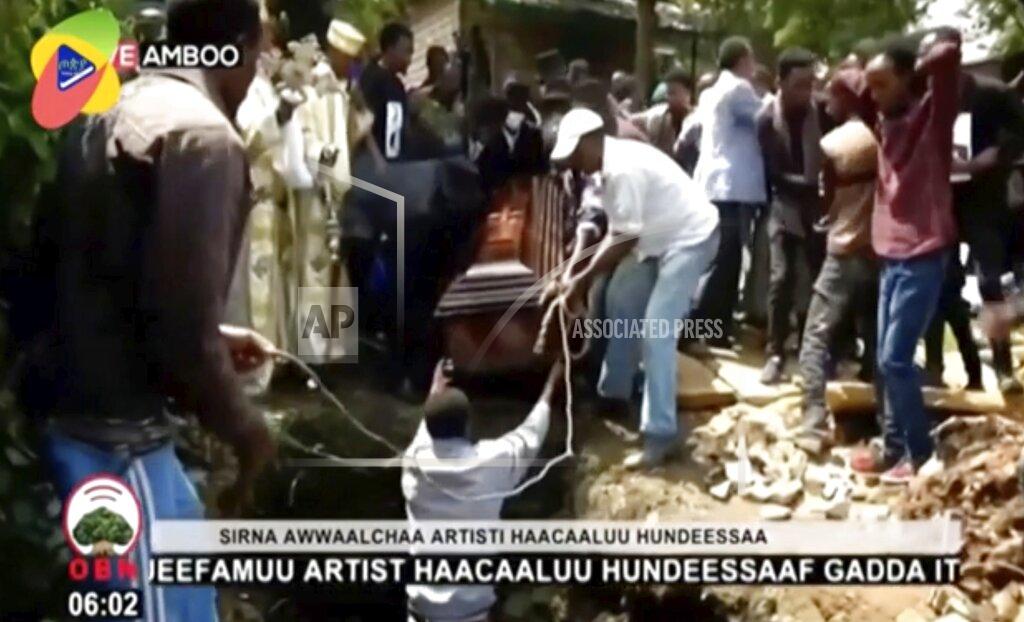 In this image taken from OBN video, the coffin carrying Ethiopia singer Hachalu Hundessa is lowered into the ground during the funeral in Ambo, Ethiopia, Thursday July 2, 2020. More than 80 people have been killed in unrest in Ethiopia after the popular singer Hachalu Hundessa was shot dead this week. He was buried Thursday amid tight security. He had been a prominent voice in anti-government protests that led to a change in leadership in 2018. (OBN via AP)