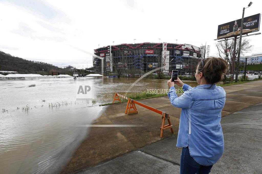 Wade Payne Michelle Harper of Masontown, Pa. takes a photo of water flooding the vendor area as races for both the Truck Series and NASCAR Cup Series auto race were postponed due to inclement weather at Bristol Motor Speedway, Sunday, March 28, 2021, in Bristol, Tenn. (AP Photo/Wade Payne)