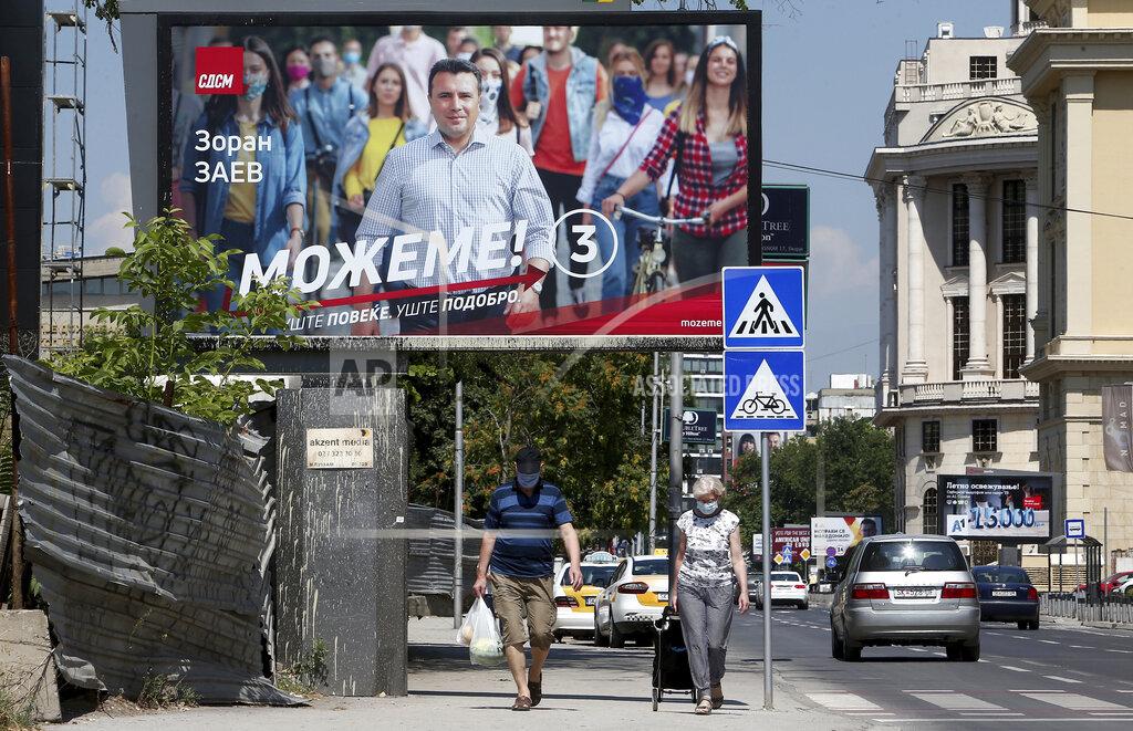 Boris Grdanoski A couple wearing face masks to protect against coronavirus, walk under an electoral poster of the leader of the ruling Social Democrats Zoran Zaev, in a street in Skopje, North Macedonia on Saturday, July 11, 2020. North Macedonia holds its first parliamentary election under its new country name this week, with voters heading to the polls during an alarming spike of coronavirus cases in the small Balkan nation. (AP Photo/Boris Grdanoski)