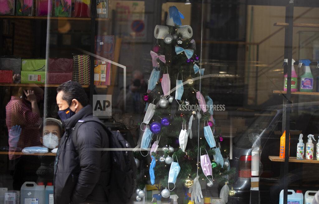 Paul White A christmas tree decorated with face masks and toilet rolls is displayed in a store in the street in Madrid, Spain, Thursday, Dec. 17, 2020. Some of Spain's regions are tightening health restrictions for the Christmas holidays with new COVID-19 cases already on the rise again. (AP Photo/Paul White)