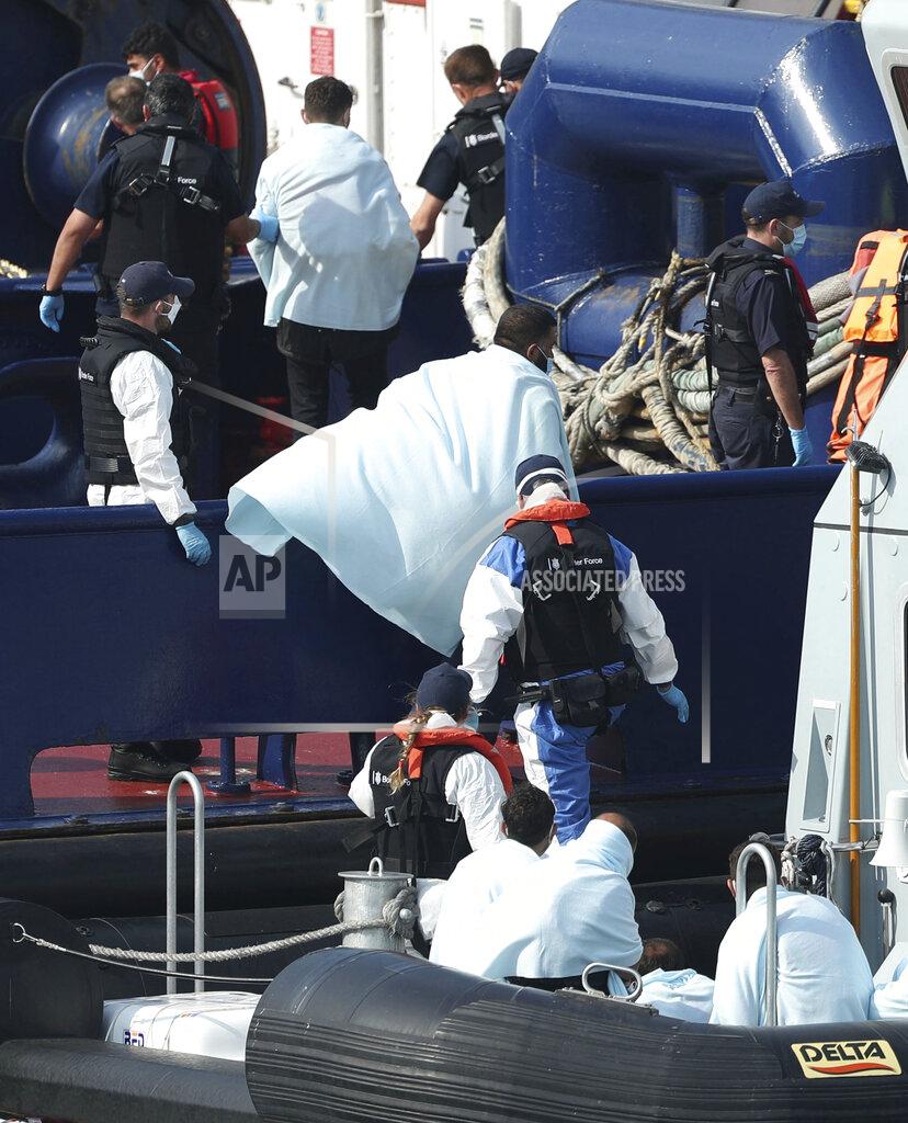 A Border Force vessel brings a group of people thought to be migrants into the port city of Dover, southern England, Sunday Aug. 9, 2020. Many migrants have used small craft during the recent hot calm weather to make the dangerous journey from northern France, to cross the busy shipping lanes of The Channel to reach Britain. (Yui Mok/PA via AP)