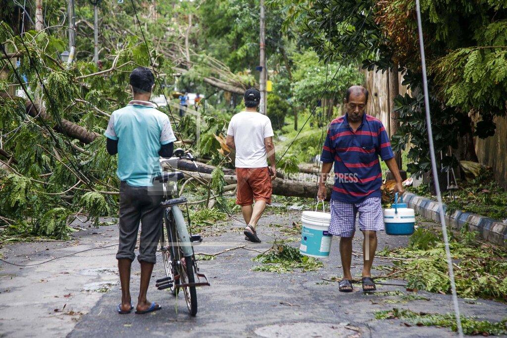 Bikas Das An Indian man carries drinking water from a nearby source and walks past trees fallen after Cyclone Amphan hit the region in Kolkata, India, Thursday, May 21, 2020. A powerful cyclone ripped through densely populated coastal India and Bangladesh, blowing off roofs and whipping up waves that swallowed embankments and bridges and left entire villages without access to fresh water, electricity and communications. (AP Photo/Bikas Das)