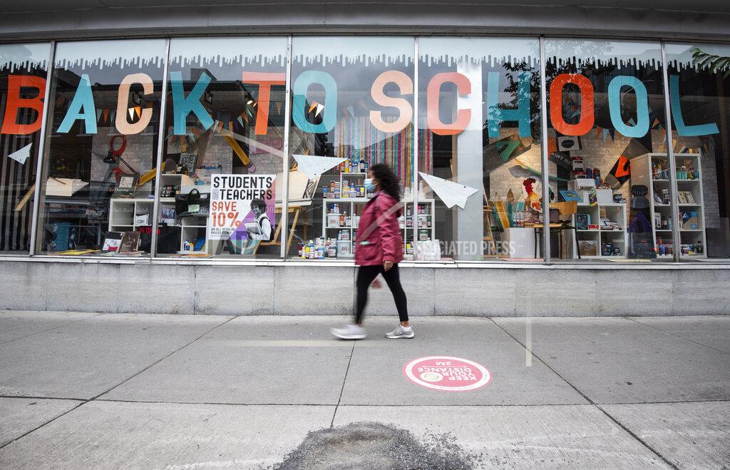 Justin Tang A person in a face mask walks past a storefront advertising their back to school sale, in Ottawa, Ontario, on the Labour Day long weekend, Monday, Sept. 7, 2020, in the midst of the COVID-19 pandemic. (Justin Tang/The Canadian Press via AP)