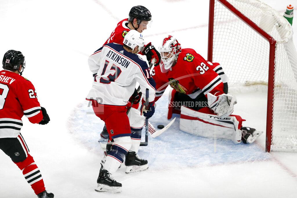 Jeff Haynes Chicago Blackhawks goaltender Kevin Lankinen (32) covers up a shot by Columbus Blue Jackets right wing Cam Atkinson (13) as Blackhawks defenseman Ian Mitchell, center, defends during the first period of an NHL hockey game Sunday, Jan. 31, 2021, in Chicago. (AP Photo/Jeff Haynes)