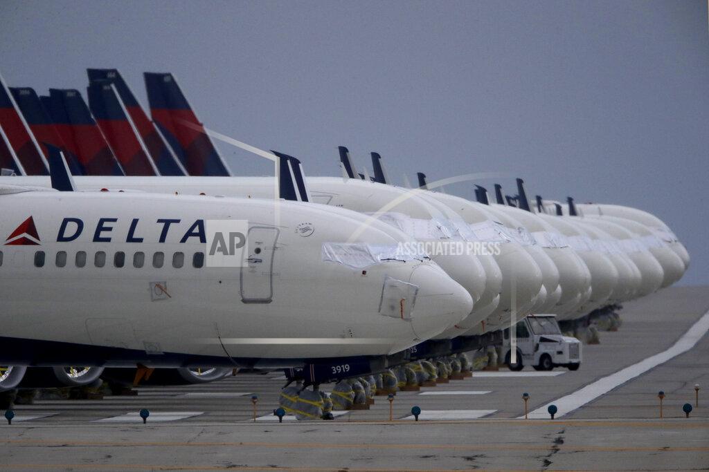 FILE - In this May 14, 2020 file photo, several dozen mothballed Delta Air Lines jets are parked on a closed runway at Kansas City International Airport in Kansas City, Mo. Delta Air Lines is reporting a $755 million loss for the fourth quarter, which brings its loss for all of 2020 to more than $12 billion. And Delta gave a cautious outlook Thursday, Jan. 14, 2021, for the first quarter of 2021, saying it expects to lose $10 million to $15 million a day in the next three months. (AP Photo/Charlie Riedel, File)