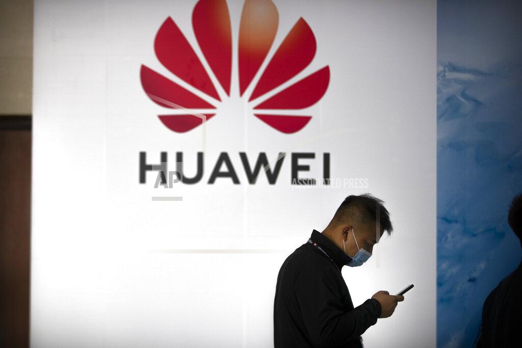 FILE - In this Oct. 14, 2020, file photo, a man wearing a face mask to protect against the coronavirus walks past a billboard advertising Chinese technology firm Huawei at the PT Expo in Beijing. Chinese tech giant Huawei, one of the biggest makers of smartphones and switching equipment, said Friday, Oct. 23, 2020 its revenue rose 9.9% in the first nine months of this year, but growth slowed due to U.S. sanctions and the coronavirus pandemic. (AP Photo/Mark Schiefelbein, File)