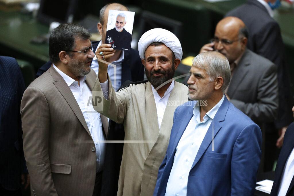 Vahid Salemi A cleric lawmaker holds a photo of Iranian Gen. Qassem Soleimani, who was killed in Iraq in a U.S. drone attack in early January 2020, during the inauguration of Iran's new parliament, in Tehran, Iran, Wednesday, May, 27, 2020. Iran has convened its newly elected parliament, dominated by conservative lawmakers and under strict social distancing regulations, as the country struggles to curb the spread of coronavirus that has hit the nation hard. Iran is grappling with one of the deadliest outbreaks in the Middle East. (AP Photo/Vahid Salemi)