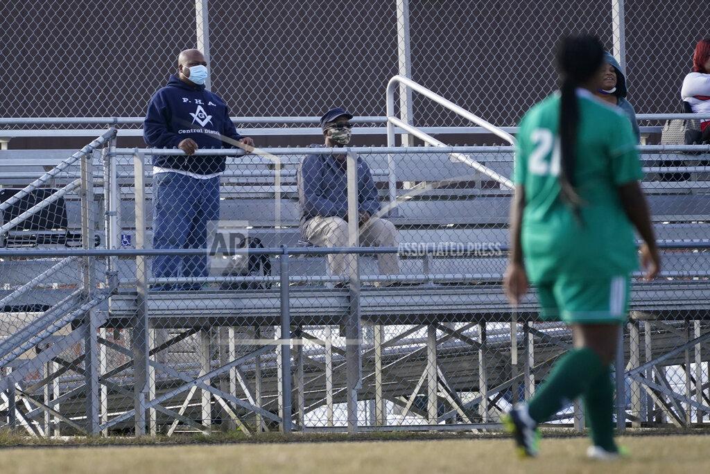 Darron Cummings Larry Brown, left, and his father, John Brown, watch Larry's daughter, Justys Glenn, right, play in a soccer game, Wednesday, Sept. 30, 2020, in Indianapolis. He didn’t die after contracting COVID-19, but he’s coming to terms with the fact that his life might never be the same. (AP Photo/Darron Cummings)