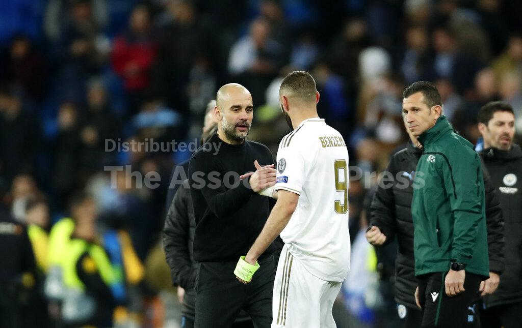 Manchester City's head coach Pep Guardiola, front left, shakes hands with Real Madrid's Karim Benzema at the end of the Champions League, round of 16, first leg soccer match between Real Madrid and Manchester City at the Santiago Bernabeu stadium in Madrid, Spain, Wednesday, Feb. 26, 2020. (AP Photo/Manu Fernandez)