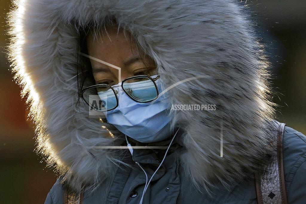 Andy Wong A woman wearing a face mask to help curb the spread of the coronavirus walks on a street in Beijing, Monday, Jan. 4, 2021. Wary of another wave of infections, China is urging tens of millions of migrant workers to stay put during next month's Lunar New Year holiday, usually the world's largest annual human migration. (AP Photo/Andy Wong)