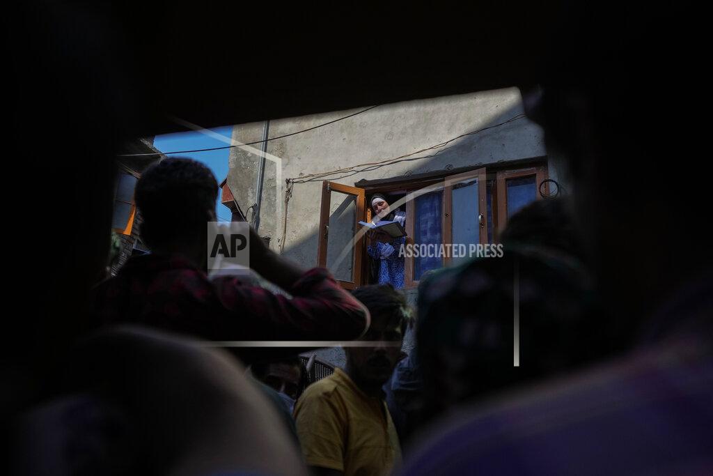 Mukhtar Khan People watch as Abida Malik, sister of Kashmiri separatist leader Yasin Malik, reads verses from the Quran as she stands at the window of her house in Srinagar, Indian controlled Kashmir, Wednesday, May 25, 2022. Shops and business establishment in some parts of Srinagar remained closed ahead of the sentence hearing of Kashmiri separatist leader Yasin Malik. Malik is being tried on charges of terrorist acts, raising funds, conspiracy, a member of a terrorist organization, and criminal conspiracy and sedition. (AP Photo/Mukhtar Khan)