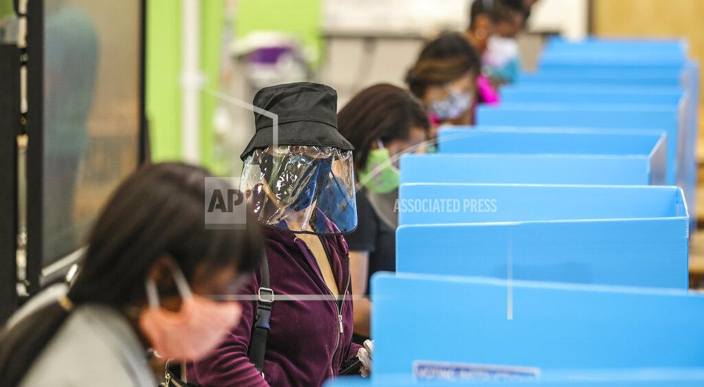 John Spink C.K. Hoffler, center, wears a face shield as she voted at Cross Keys High School in Atlanta on Tuesday, June 9, 2020. At the DeKalb County school, volunteers passed out water bottles to a crowd of 100 voters lined up for hours outside the building. (John Spink/Atlanta Journal-Constitution via AP)