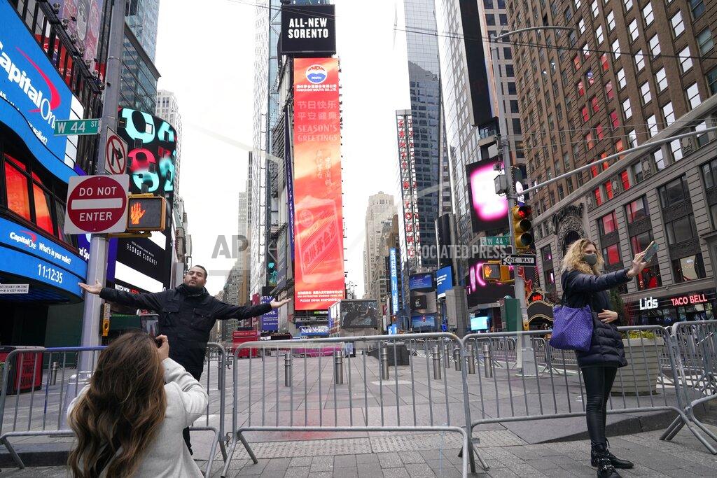 Frank Franklin Ii People pose for photographs while wearing protective masks during the coronavirus pandemic in Times Square Thursday, Dec. 31, 2020, in New York. (AP Photo/Frank Franklin II)