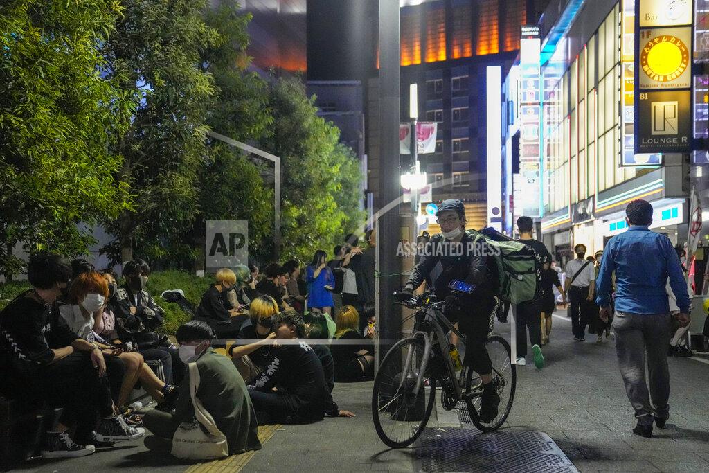 Kiichiro Sato People walk around and gather at a bar after government imposed 8 p.m. closing time for restaurants and bars under Tokyo's fourth state of emergency Saturday, July 17, 2021, in Tokyo. The latest state of emergency has asked restaurants and bars to close by 8 p.m., if not entirely. This has pushed people to drink outside, although many bars remain open and bustling with customers who are defying the rules and expressing frustration and indifference. (AP Photo/Kiichiro Sato)
