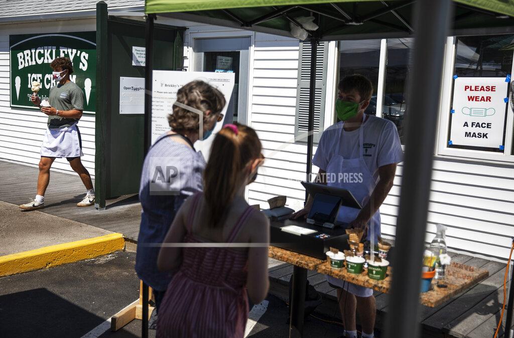 David Goldman Employees serve customers with masks at a Brickley's Ice Cream shop, one of two stores, in Narragansett, R.I., Wednesday, July 29, 2020. The other nearby location closed when teenage workers were harassed by customers who refused to wear a mask or socially distance. Disputes over masks and mask mandates are playing out at businesses, on public transportation and in public places across America and other nations. (AP Photo/David Goldman)