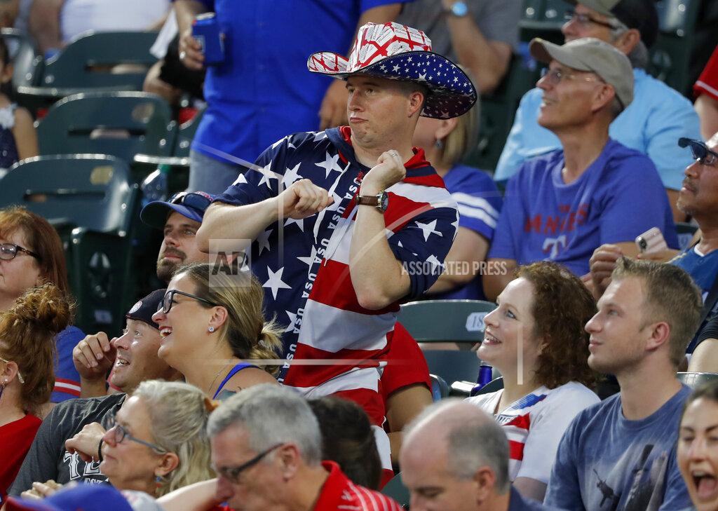 Tony Gutierrez FILE - In this July 4, 2019, file photo, a fan dressed for the Fourth of July holiday dances to music in the stadium in the fifth inning of a baseball game between the Los Angeles Angels and the Texas Rangers in Arlington, Texas. Major League Baseball owners gave the go-ahead Monday, May 11, 2020, to making a proposal to the players’ union that could lead to the coronavirus-delayed season starting around the Fourth of July weekend in ballparks without fans, a plan that envisioned expanding the designated hitter to the National League for 2020. (AP Photo/Tony Gutierrez, File)