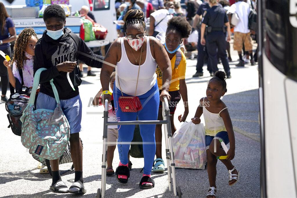 David J. Phillip Evacuees walk to board buses Tuesday, Aug. 25, 2020, in Galveston, Texas. The evacuees are being taken to Austin, Texas, as Hurricane Laura heads toward the Gulf Coast. (AP Photo/David J. Phillip)
