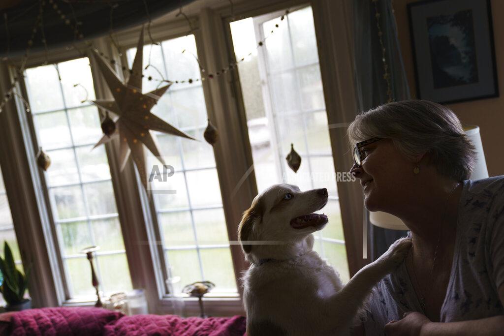 David Goldman Ellen Booth, 57, who is studying to become a certified medical coder, plays with her dog, Rumble, at her home in Coventry, R.I., Monday, May 17, 2021. When the restaurant she worked for closed last year, Booth said it gave her "the kick I needed." She started a year-long class to learn to be a medical coder. When her unemployment benefits ran out two months ago, she started drawing on her retirement funds. Booth hopes to pass her upcoming exam and soon hit the job market. (AP Photo/David Goldman)
