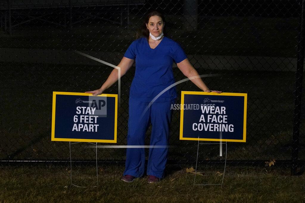 Charlie Riedel Emergency room nurse L'Erin Ogle poses with coronavirus signs after getting off a 12-hour shift at a nearby hospital where she works Monday, March 8, 2021, in Overland Park, Kan. After a year of working long hours taking care of COVID-19 patients, Ogle feels obligated to speak out when she sees misinformation related to the pandemic in her community. (AP Photo/Charlie Riedel)