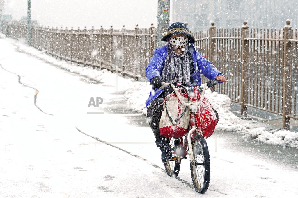 Kathy Willens A woman rides a bicycle across the Brooklyn Bridge during a snowstorm, Sunday, Feb. 7, 2021, in the Brooklyn borough of New York. It was the second time in less than a week the area has been buffeted by heavy snowfall. (AP Photo/Kathy Willens)
