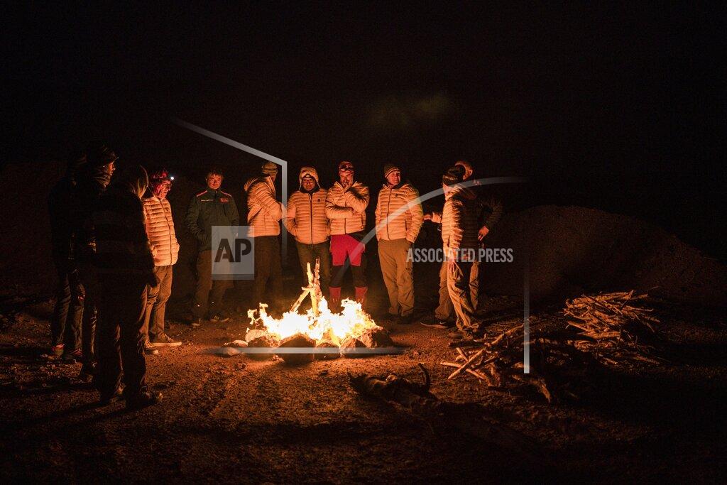 Bernat Armangue In this Sunday, Jan. 12, 2020 photo, Dakar pilots and medics gather around a bonfire after stage seven of the Dakar Rally in Wadi Al Dawasir, Saudi Arabia. Formerly known as the Paris-Dakar Rally, the race was created by Thierry Sabine after he got lost in the Libyan desert in 1977. Until 2008, the rallies raced across Africa, but threats in Mauritania led organizers to cancel that year's event and move it to South America. It has now shifted to Saudi Arabia. The race started on Jan. 5 with 560 drivers and co-drivers, some on motorbikes, others in cars or in trucks. Only 41 are taking part in the Original category. (AP Photo/Bernat Armangue)