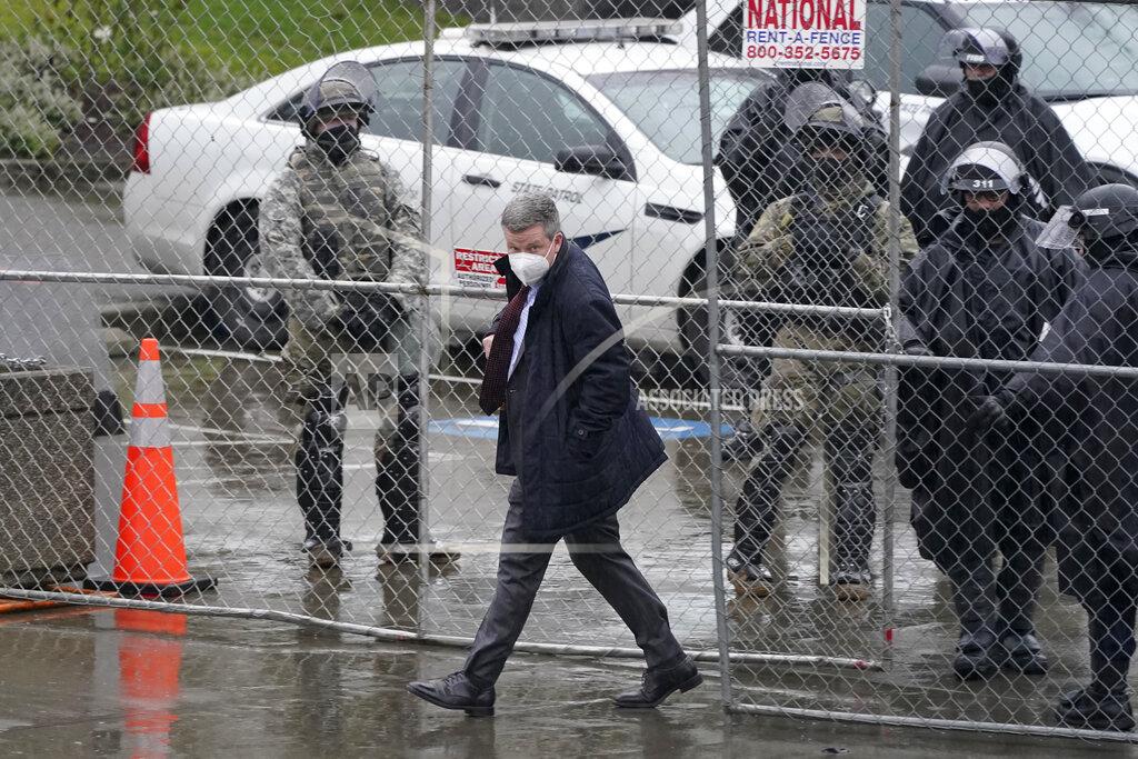 Ted S. Warren FILE - In this Jan. 11, 2021 file photo, Sen. Mark Mullet, D-Issaquah, walks past members of the Washington National Guard and Washington State Patrol troopers as he passes through a perimeter fence gate opening on the first day of the 2021 legislative session in Olympia, Wash. The 2021 session of the Washington Legislature ended Sunday, April 25 and lawmakers had no shortage of weighty topics to consider while having to conduct their work amid a pandemic that meant most meetings and votes were conducted remotely. The Capitol building was also closed to the public since last year due to the COVID-19 pandemic, and was surrounded by security fencing and national guard members at times due to fears of protests. (AP Photo/Ted S. Warren, File)