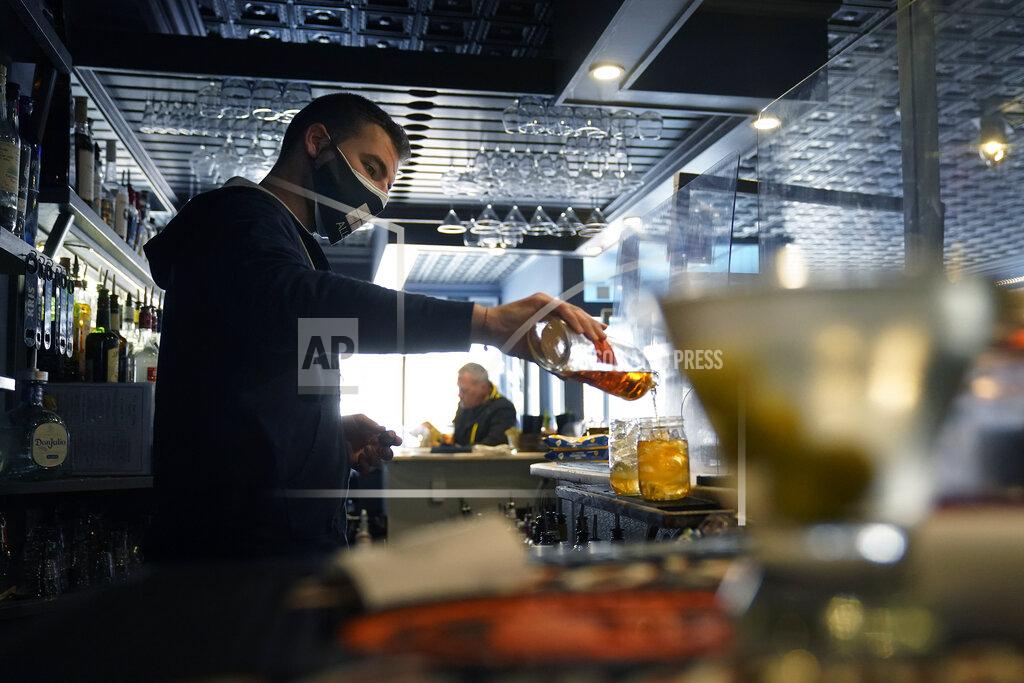 Steven Senne Bartender Denis Angelov, of Provincetown, Mass., pours drinks at Tin Pan Alley restaurant, Tuesday, April 6, 2021, in Provincetown. Hotels, restaurants and other businesses in tourist destinations are warning that hiring challenges during the coronavirus pandemic could force them to pare back operating hours or curtail services just as they’re eyeing a bounce-back summer. (AP Photo/Steven Senne)