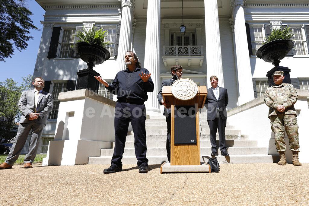State Health Officer Dr. Thomas Dobbs, at the podium, speaks about establishment of two one-day COVID-19 testing centers in Clarksdale and Olive Branch Friday, during a news conference outside the Governor's Mansion, while Gov. Tate Reeves, second from right, listens, with members of the state's COVID-19 response team, Thursday, March 26, 2020 in Jackson, Miss. The testing centers will be run by the Mississippi State Department of Health and the University of Mississippi Medical Center. (AP Photo/Rogelio V. Solis)