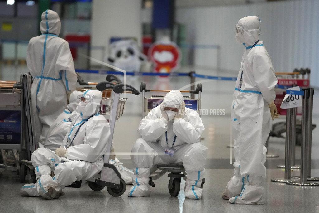 Frank Augstein Olympic workers in protective clothing take a rest after helping travellers at Beijing Capital International airport after the 2022 Winter Olympics, Monday, Feb. 21, 2022, in Beijing, China. (AP Photo/Frank Augstein)