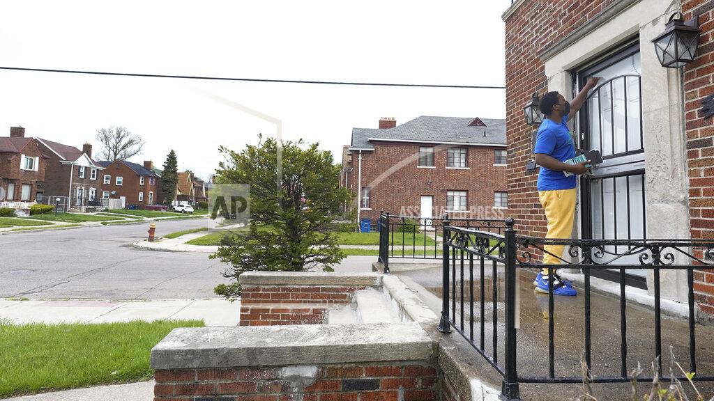 Paul Sancya Robert Day knocks on a door before leaving a flyer on a home in Detroit, Tuesday, May 4, 2021. Officials are walking door-to-door to encourage residents of the majority Black city to get vaccinated against COVID-19 as the city's immunization rate lags well behind the rest of Michigan and the United States. (AP Photo/Paul Sancya)