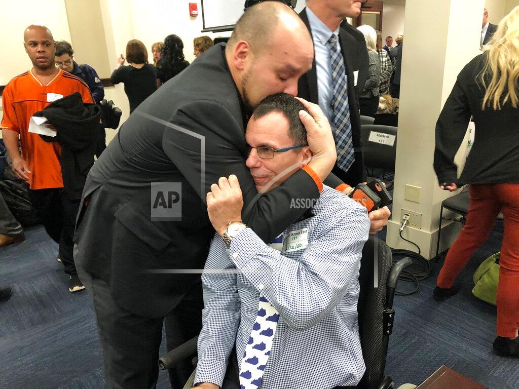 In this Wednesday, Feb. 12, 2020, photo, Eric Crawford, center right, is hugged by another medical marijuana advocate after a bill to legalize medical cannabis in Kentucky was approved by a state House committee, in Frankfort, Ky. Kentucky House Speaker David Osborne said Friday that the bill could possibly come up for a House vote as soon as next week. (AP Photo/Bruce Schreiner)