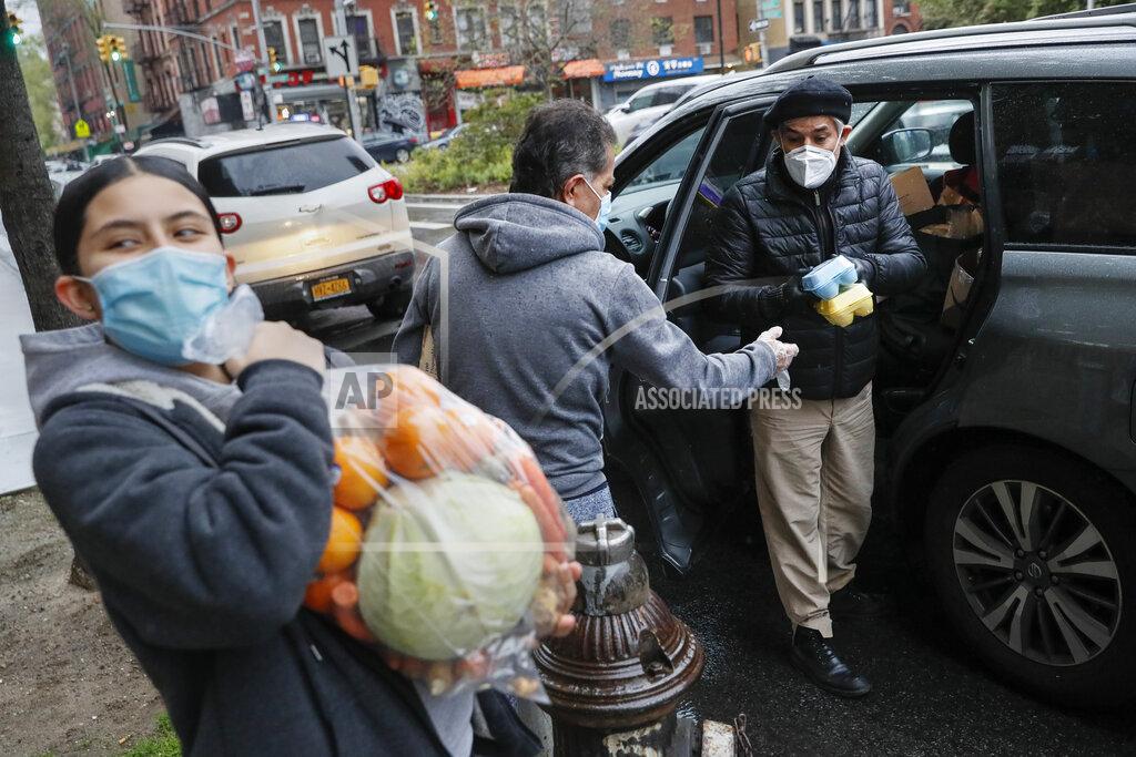 John Minchillo Fabian Arias, a Lutheran pastor with Saint Peter's Church in Manhattan, right, hands eggs to a father as he makes food donation delivery to an individual family, Friday, May 8, 2020, in New York. (AP Photo/John Minchillo)