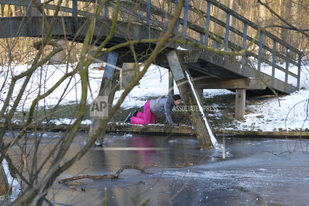 Mike Corder A skater crawls under a bridge to avoid thin ice on a lake in The Hague, Netherlands, Friday, Feb. 12, 2021. With many lakes and canals in the Netherlands frozen over, Dutch skating fans flocked to the ice Friday, causing a headache for authorities trying to enforce social distancing measures to stop the spread of the coronavirus. (AP Photo/Mike Corder)