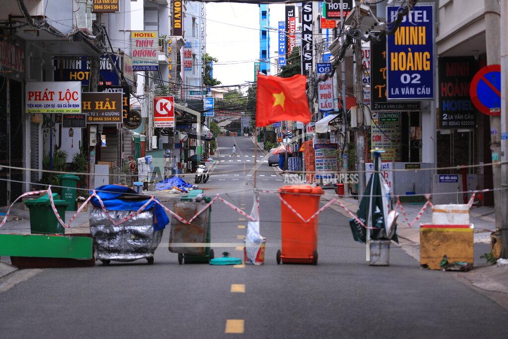 Hau Dinh An alley is blocked with trash can and a Vietnamese flags in Vung Tau, Vietnam, Monday, Sept. 13, 2021. In Vung Tau, just outside Ho Chi Minh city, streets are sealed and checkpoints are set up to control the movement of people. Barbed wire, door panels, steel sheets, chairs and tables are among materials being used to fence up alleys and isolate neighborhoods.(AP Photo/Hau Dinh)