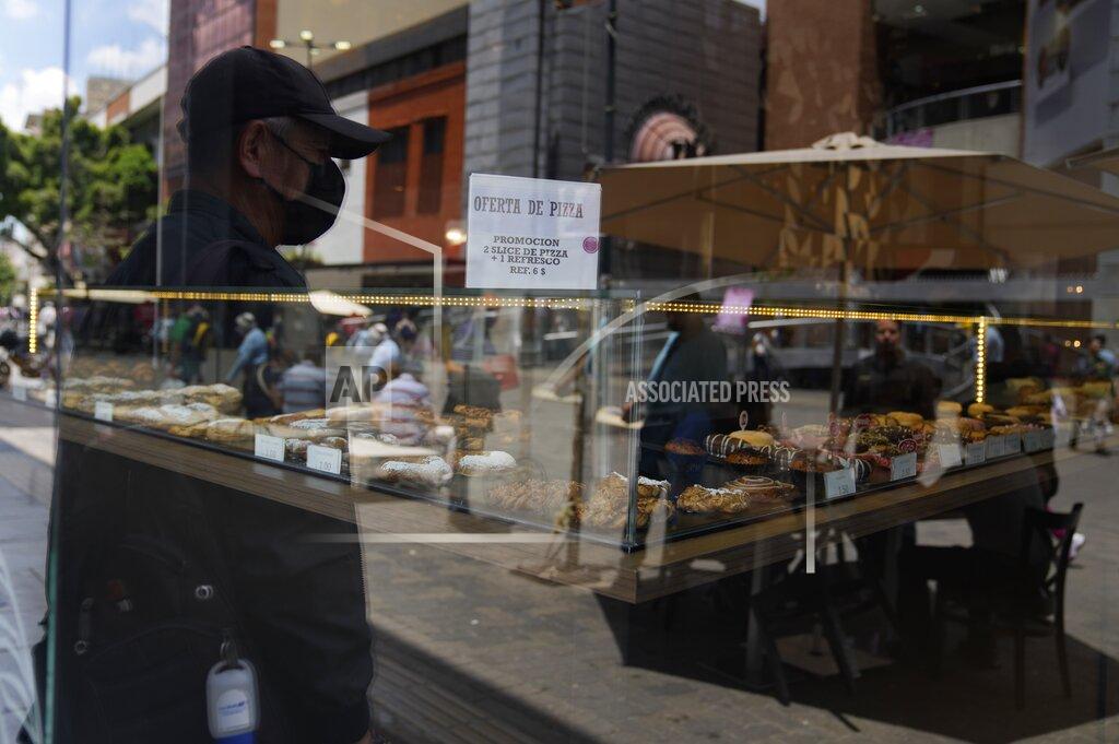 Ariana Cubillos A sign taped to a storefront advertises a slice of pizza and a soda for 6 U.S. dollars, in Caracas, Venezuela, Thursday, May 12, 2022. A new tax law approved by the Venezuelan government, that went into effect in March, applies a 3% tax charge on transactions paid in foreign currency. (AP Photo/Ariana Cubillos)