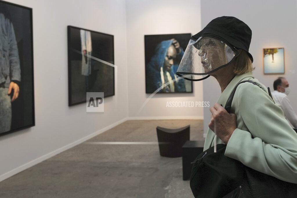 Francois Mori A visitor, wearing a protective face mask as a precaution against the coronavirus, looks on during the private view of Art Paris at the Grand Palais in Paris, Wednesday Sept. 9, 2020. Fears and restrictions over the coronavirus have caused the cancellation of all of 2020's premiere global art fairs, such as Art Basel, Frieze London, and Art Basel in Miami Beach, stymieing the main commercial artery of the multi-million-dollar industry.But organizers of Art Paris, France's second biggest contemporary art fair, have thrown caution to the wind, and are opening their doors to thousands of visitors from Thursday in the Grand Palais for a four-day show. (AP Photo/Francois Mori)