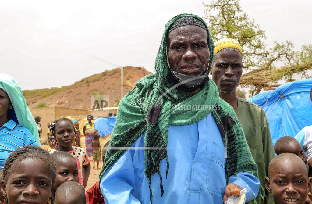 Sam Mednick Volunteer fighter Issa Tamboure, walks with his family outside his tent in a makeshift site for displaced people in Kongoussi, Burkina Faso, Thursday, June 4, 2020. With little training, few weapons, and dwindling means amid an economic downturn fueled by the coronavirus pandemic, volunteers like Tamboure, recruited by the military to help fight jihadists, say they struggle to battle the well-armed extremists. (AP Photo/Sam Mednick)