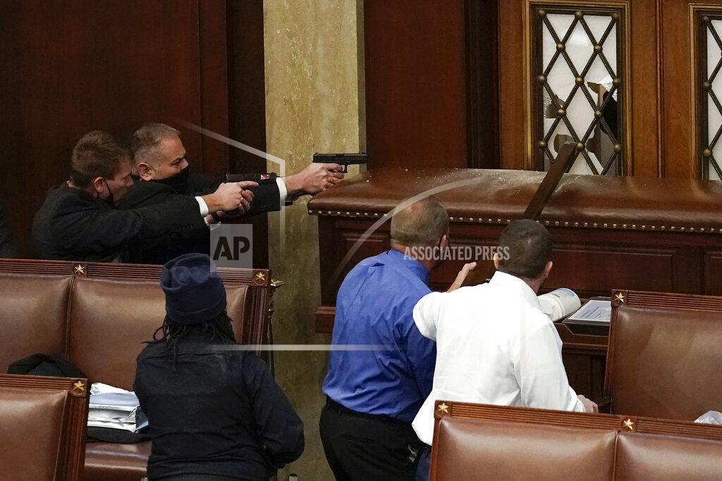 J. Scott Applewhite U.S. Capitol Police with guns drawn watch as rioters try to break into the House Chamber at the U.S. Capitol on Wednesday, Jan. 6, 2021, in Washington. (AP Photo/J. Scott Applewhite)