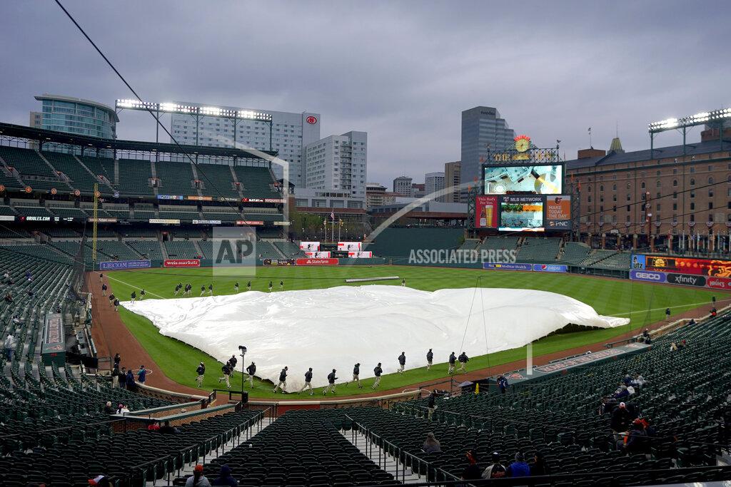 Julio Cortez Grounds crew members place a tarp over the infield at Oriole Park at Camden Yards prior to a baseball game between the Baltimore Orioles and the Seattle Mariners, Monday, April 12, 2021, in Baltimore. (AP Photo/Julio Cortez)