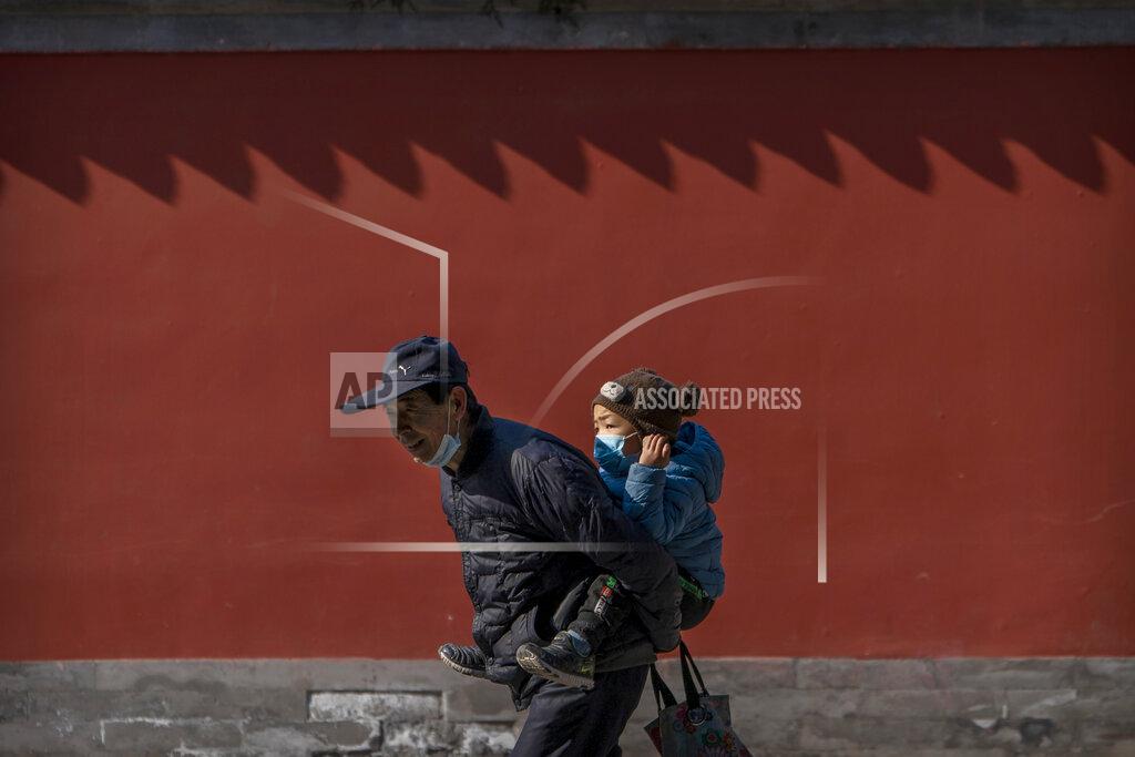 Mark Schiefelbein In this Tuesday, Feb. 9, 2021, photo, an elderly man carries a young boy on his back as he walks in a public park in Beijing. China's population grew last year, the government said Thursday, following a report that a census might have found a surprise decline, possibly adding to downward pressure on economic growth. (AP Photo/Mark Schiefelbein)
