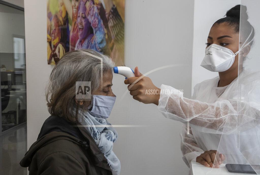 Michel Euler In this Wednesday, May 13, 2020 photo, a masked unidentified patient has her temperature checked by dental assistant Margot Daussat prior to a dental appointment at a dental office in Paris. Those with toothache that suffered through France's two-month lockdown, finally have hope to end the pain. Dental practices are cautiously re-opening and non-emergency dentist appointments are now permitted around the country, as the French government eased confinement restrictions from Monday. (AP Photo/Michel Euler)